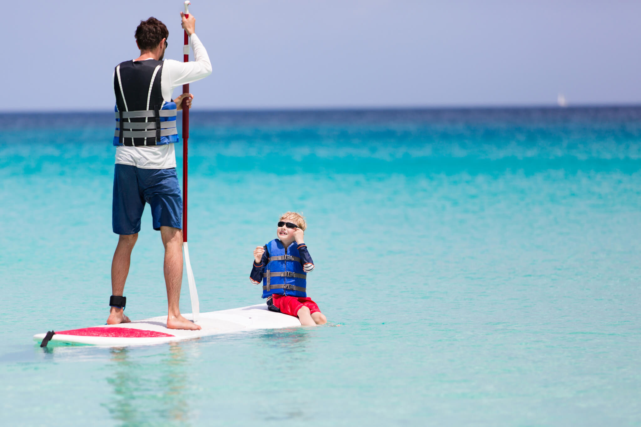 Father and sun on a paddle board in turquoise waters having a good time