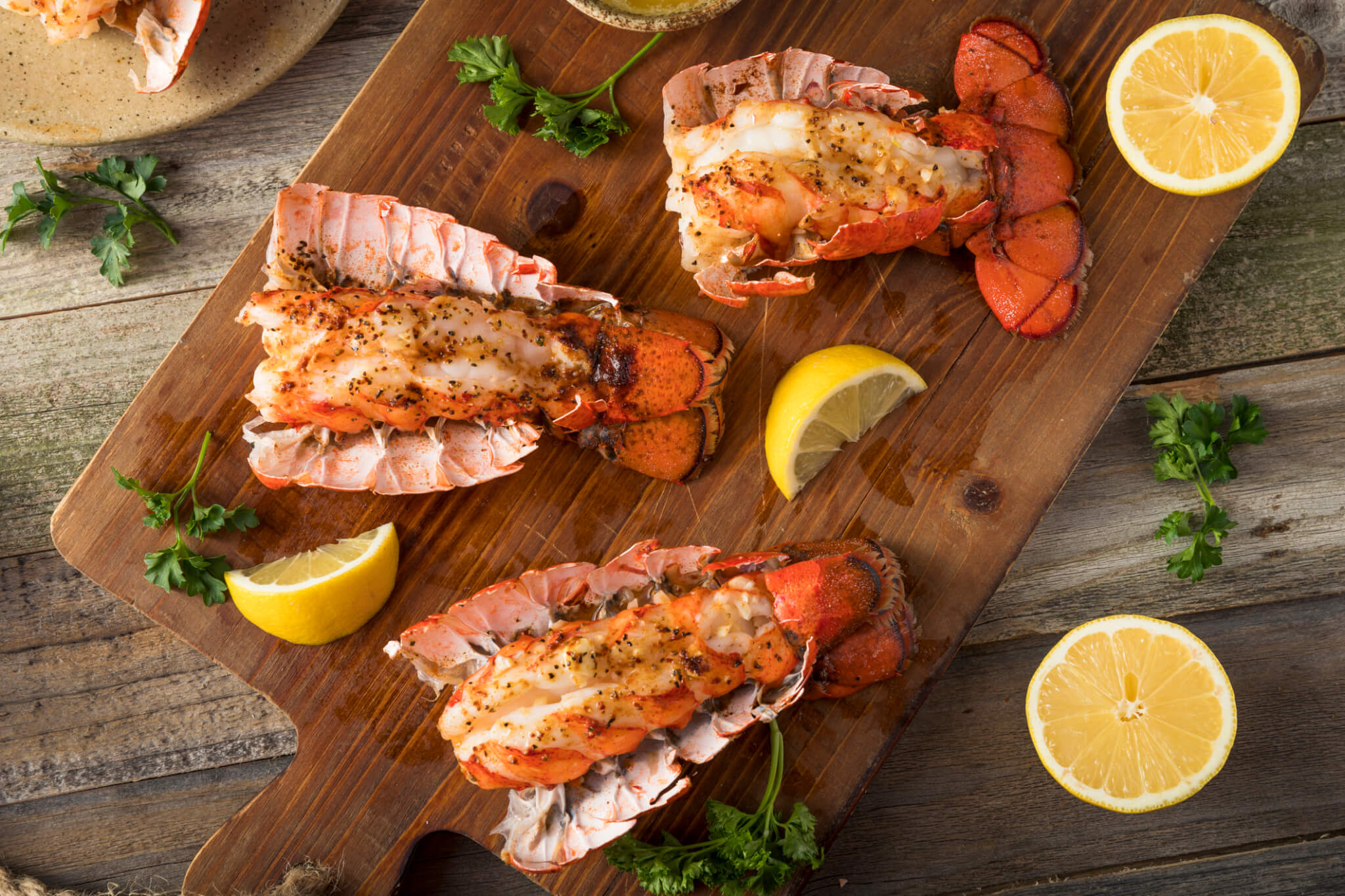 Professionally prepared lobster elegantly plated on a wooden board with lemons and herbs