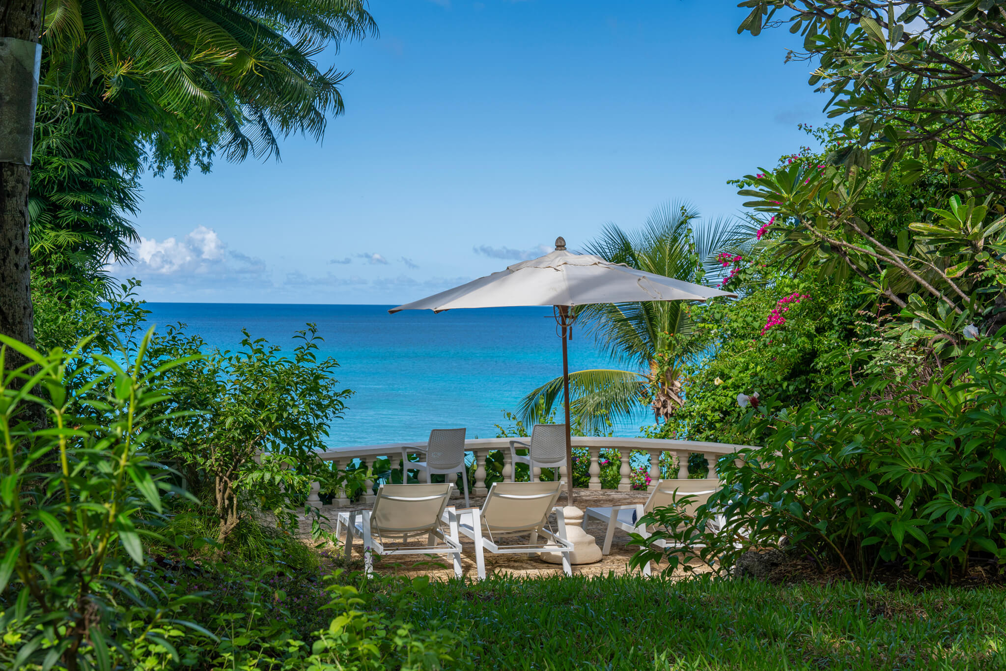 Patio surrounded by lush tropical vegetation overlooking the turquoise waters of the Caribbean Sea