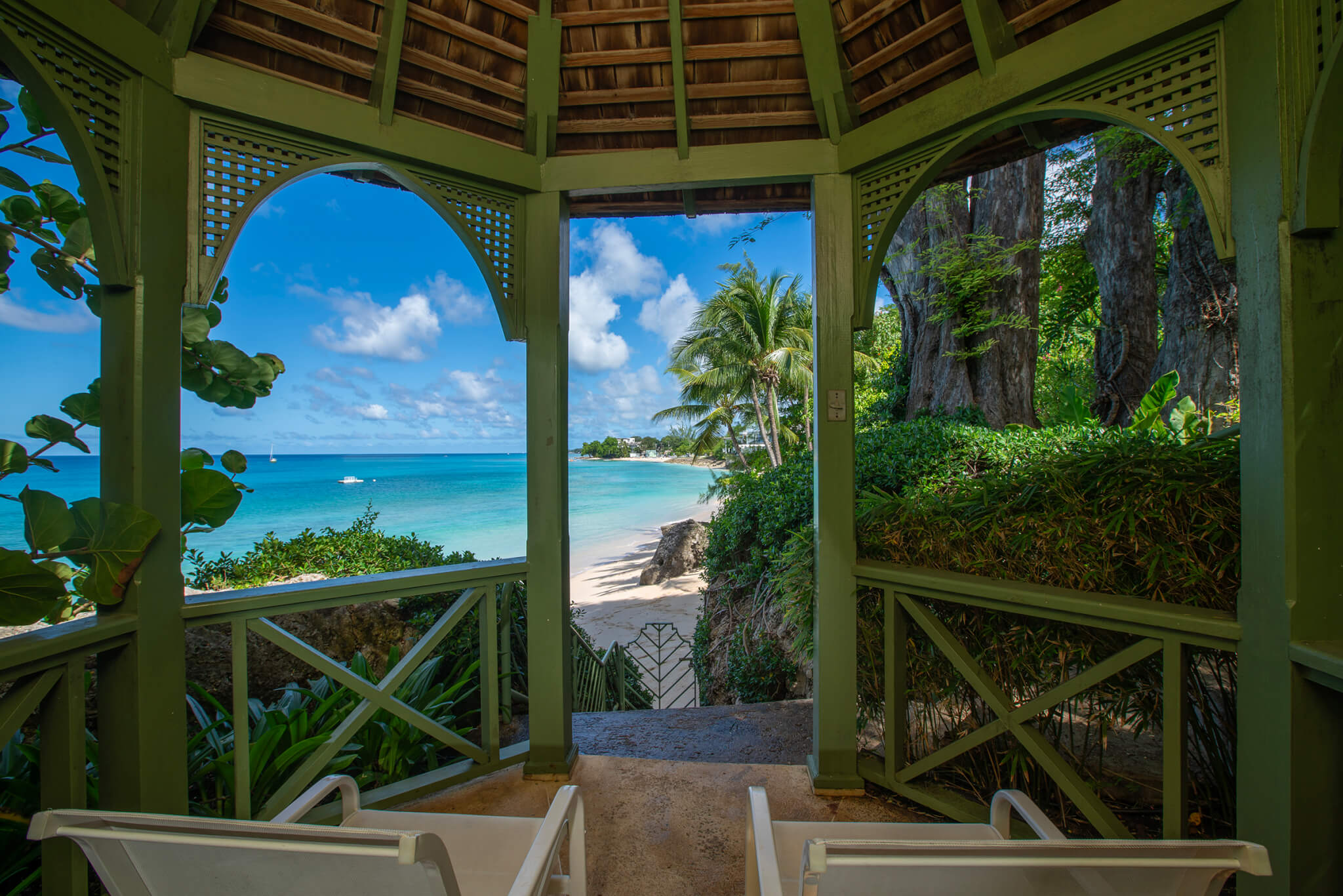 Round wooden gazebo surrounded by lush tropical vegetation and mere steps away from the pristine beach