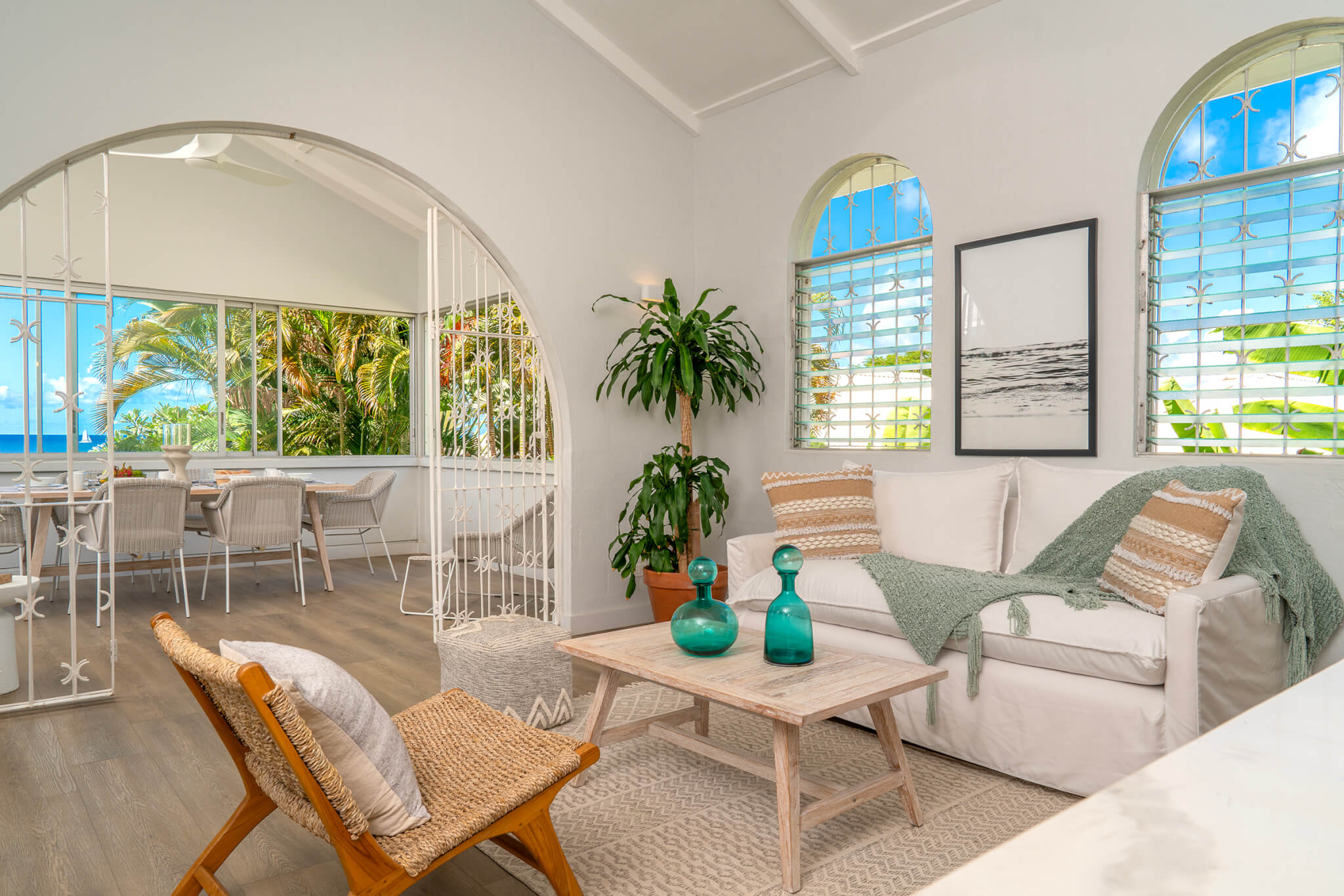 Lounge area with an L shaped white sofa and a chair with a wooden coffee table in between