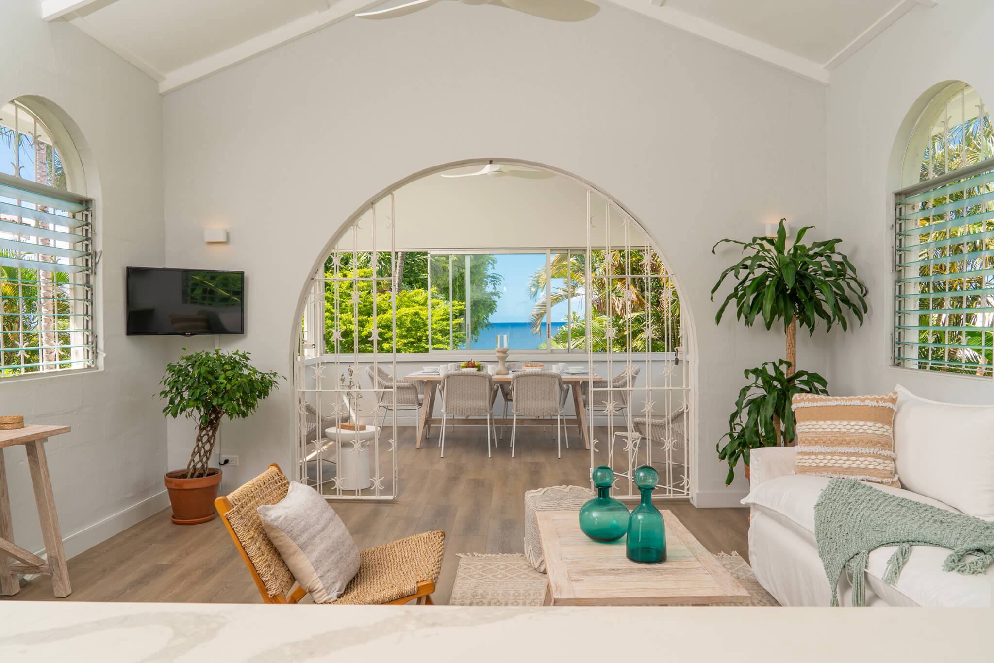 Open plan lounge and dining area with a long dining table looking over the Caribbean Sea with lush vegetation either side