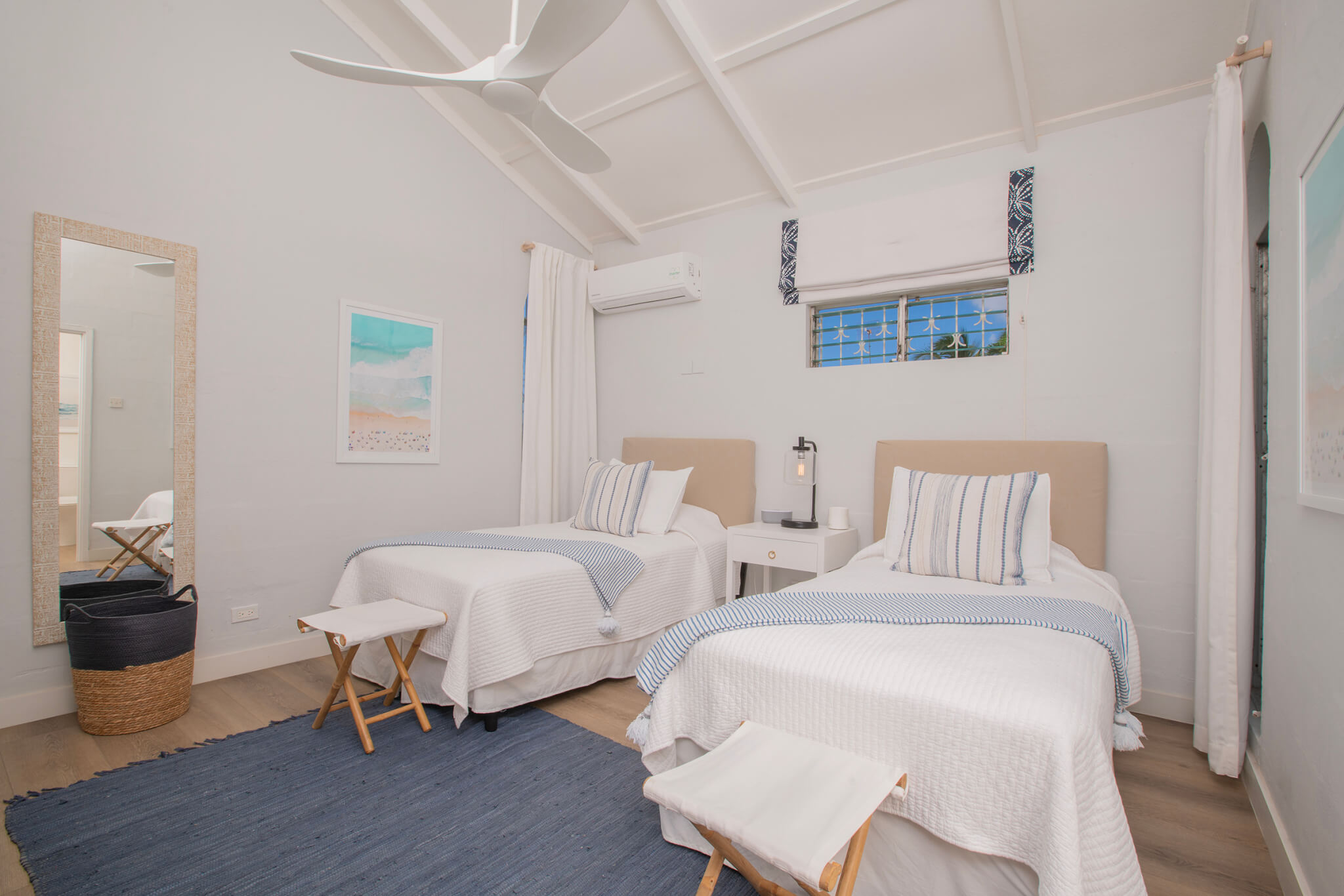 Twin bedroom with a bedside table separating the beds and a blue rug at the foot of the beds